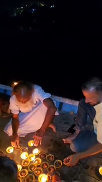 Lamps being lit by the Yamuna after dark