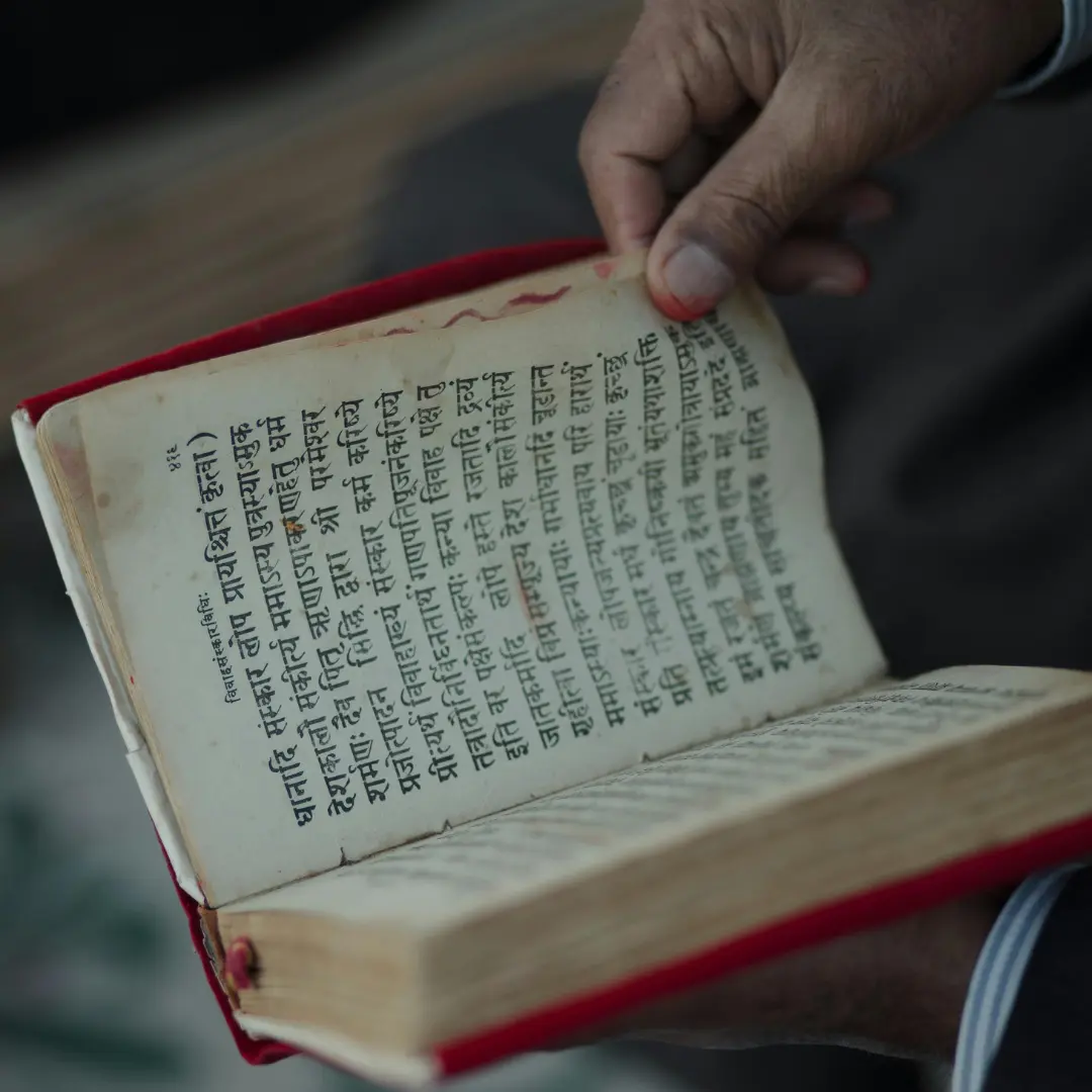 Hands holding an open Sanskrit scripture