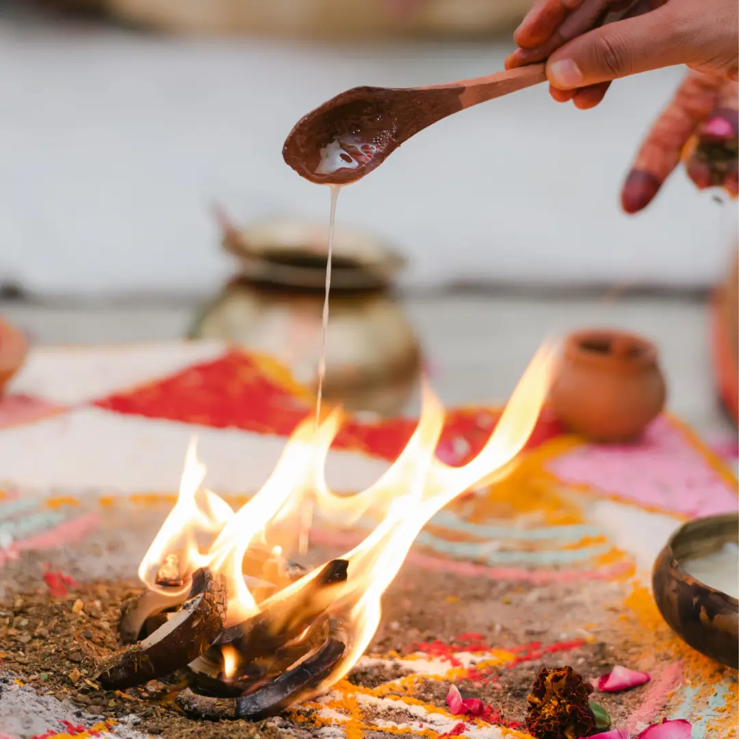 Ghee poured from a long spoon into the fire