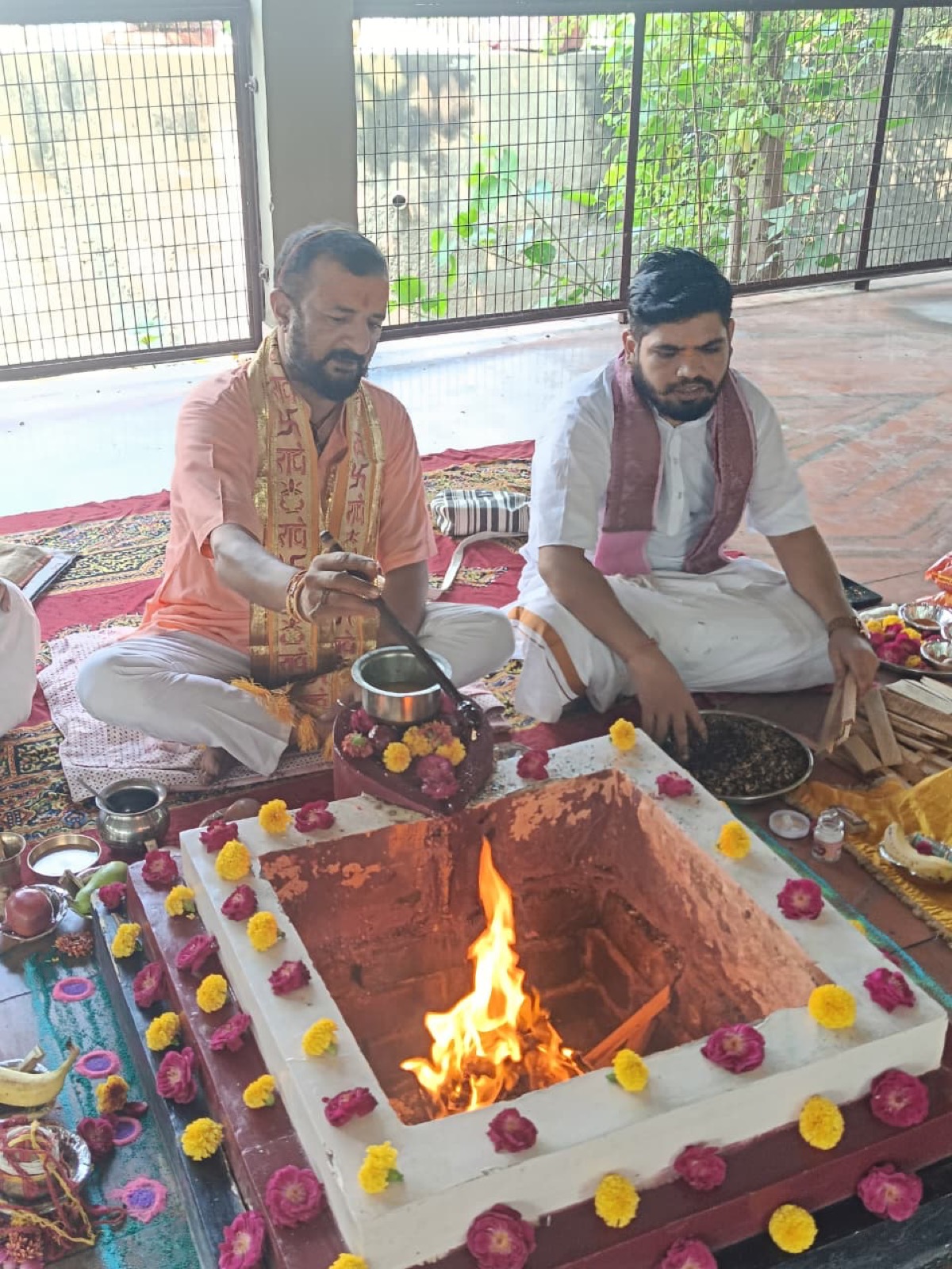 Two Brahmins at the fire kund as the fire is lit